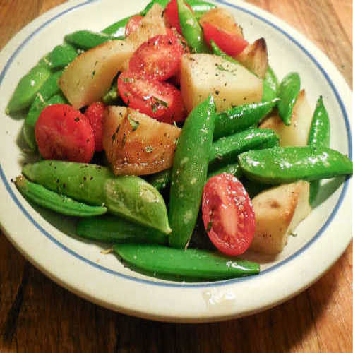 Plate of sugar snap peas, baby tomatoes and roast potatoes.