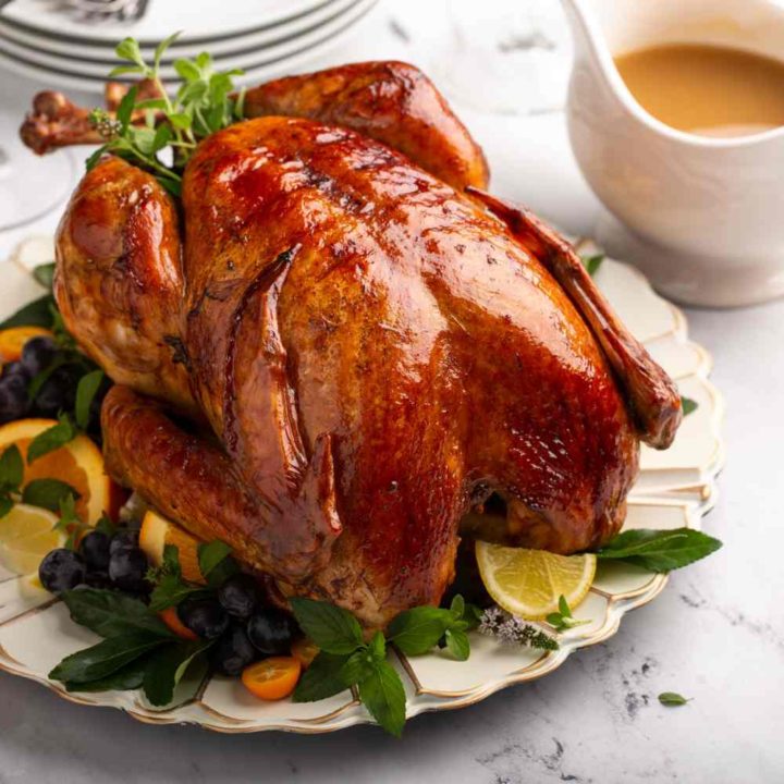 Roast turkey on a plate with lemon and herbs.