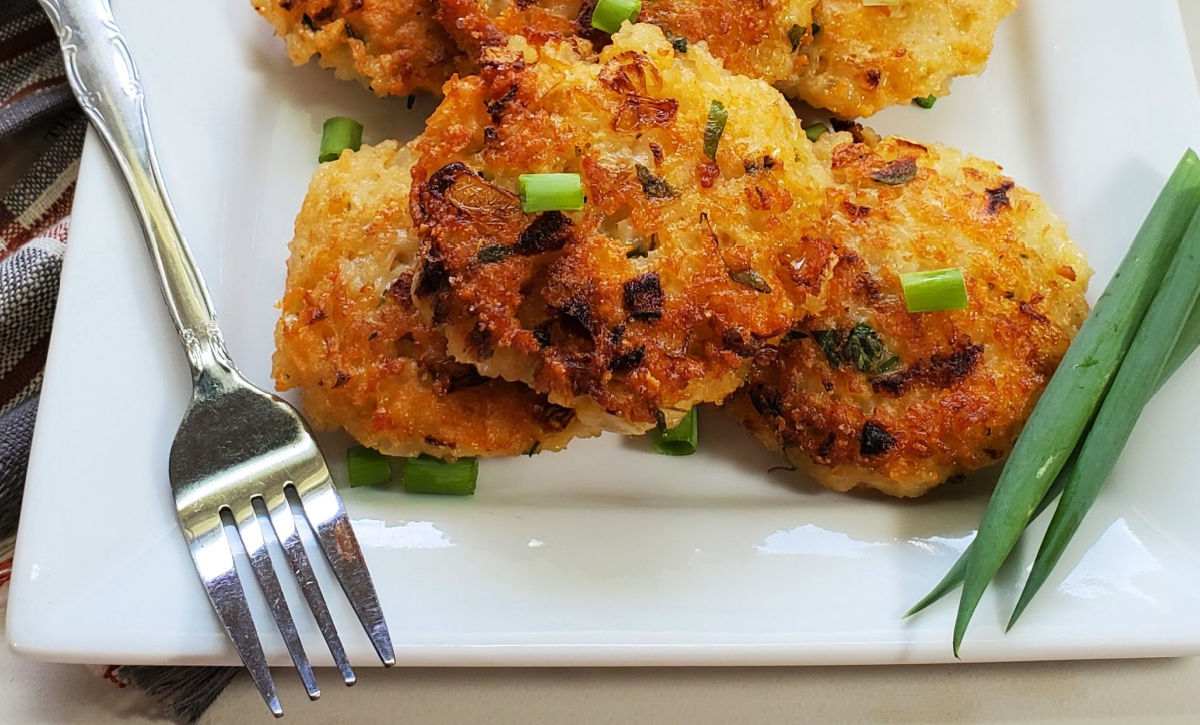 Rice fritters with spring onions and a fork on a white plate.