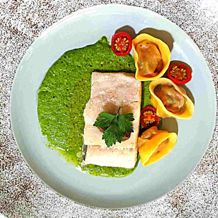 Baked barramundi on pesto with tomatoes and tortellini.