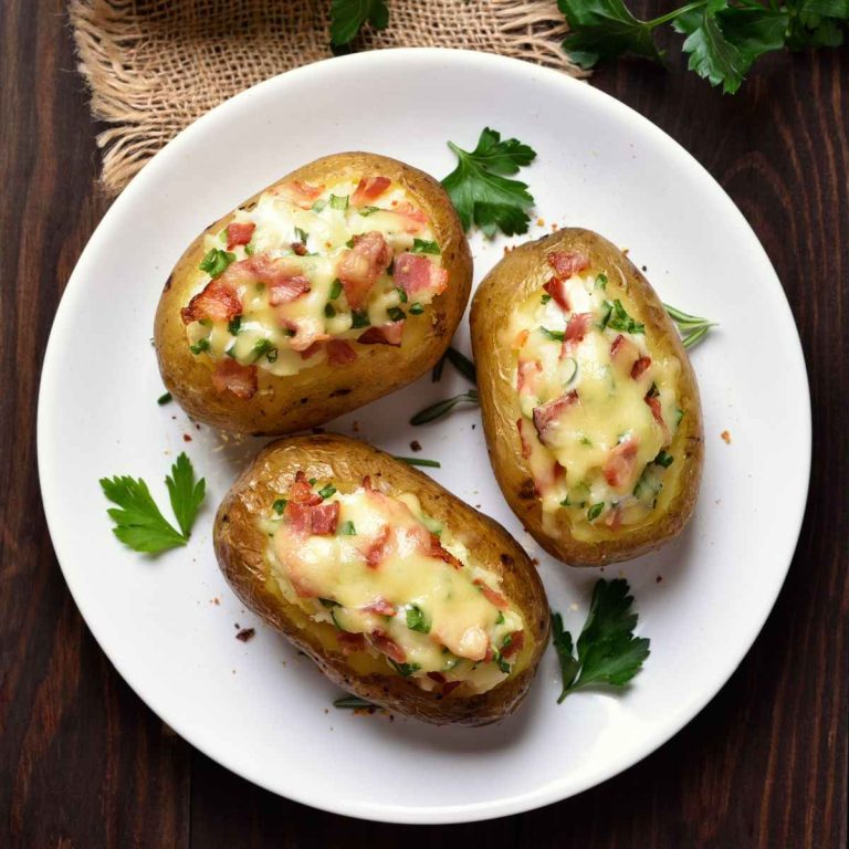 Baked stuffed potatoes on a white plate and wooden counter.