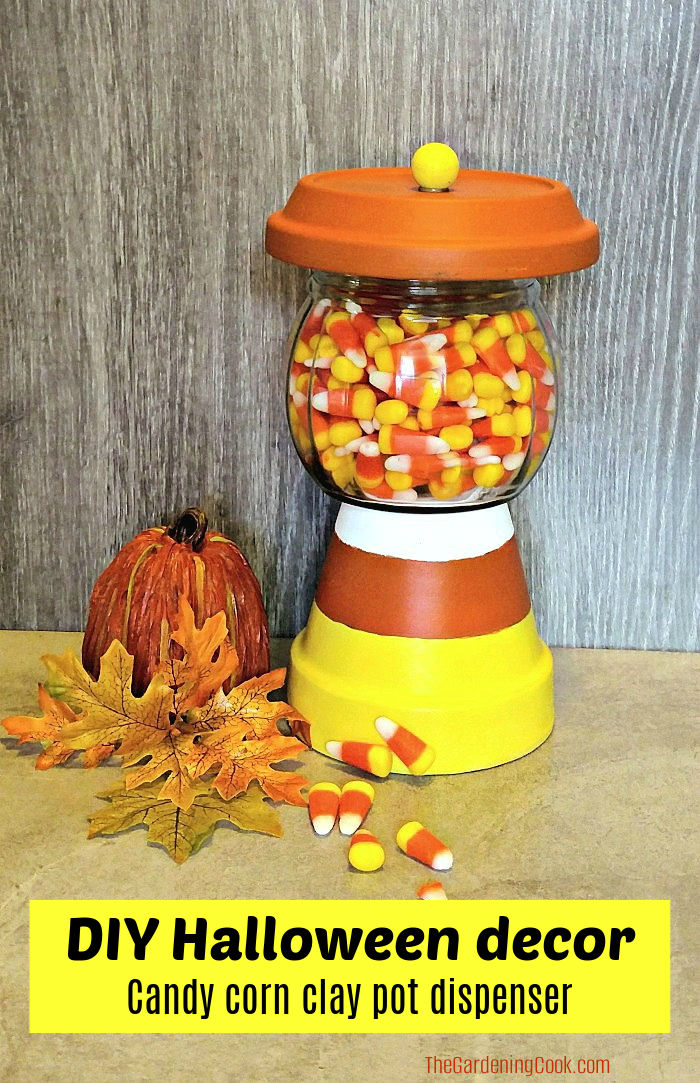 How to Make a Candy Corn Clay Pot Dispenser A painted terracotta pot, saucer and glass jar made into a Halloween candy jar. Yellow text block reads DIY Halloween decor - candy corn clay pot dispenser