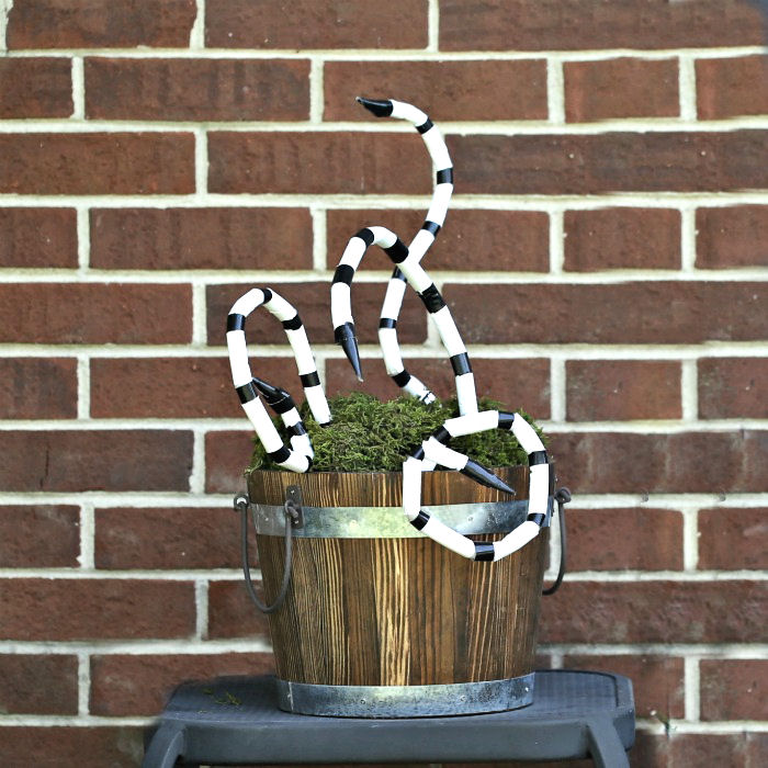 Brown basket on a table in front of a brick wall, holding DIY snakes.