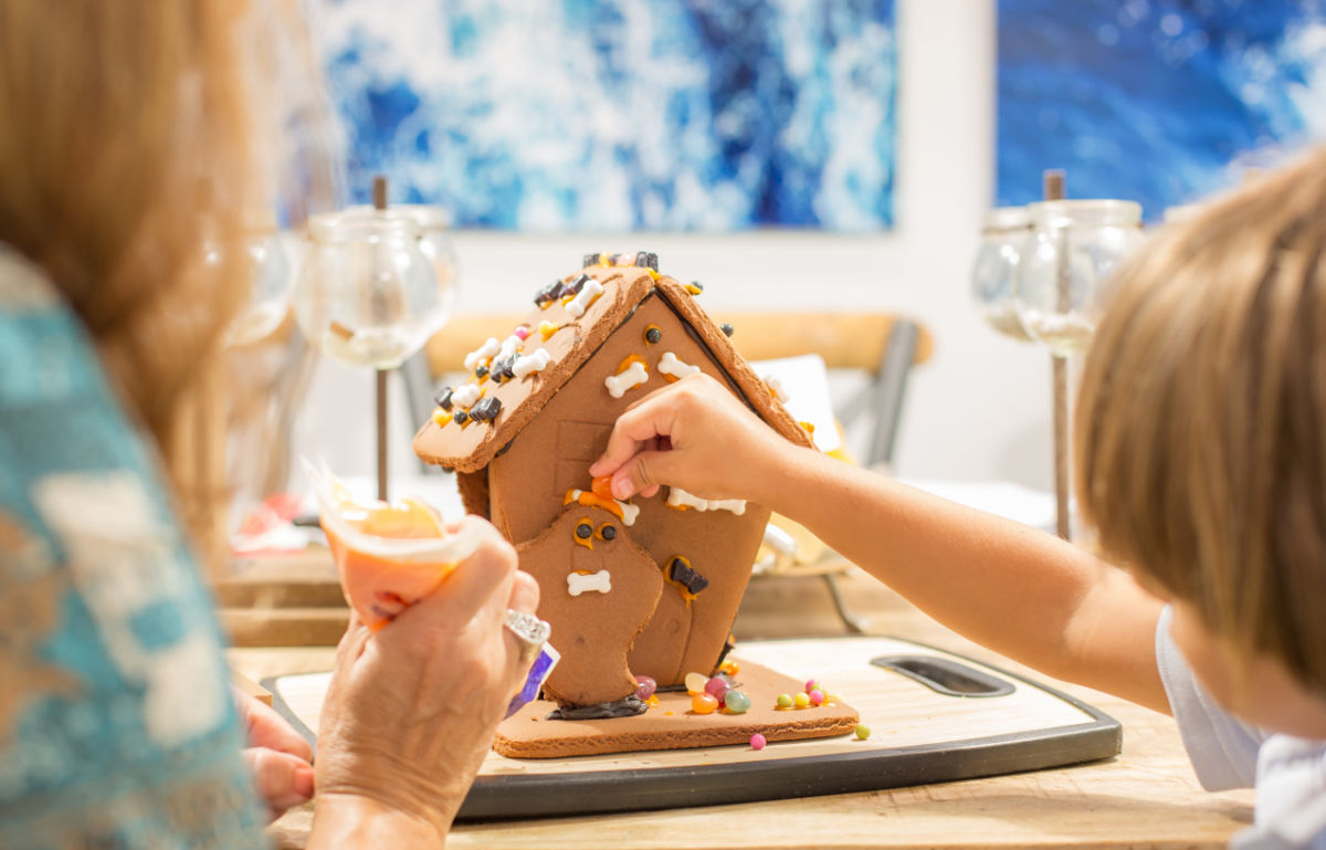 20 tips for the perfect gingerbread house. A mother and daughter making a gingerbread house in a room but a pretty blue window.