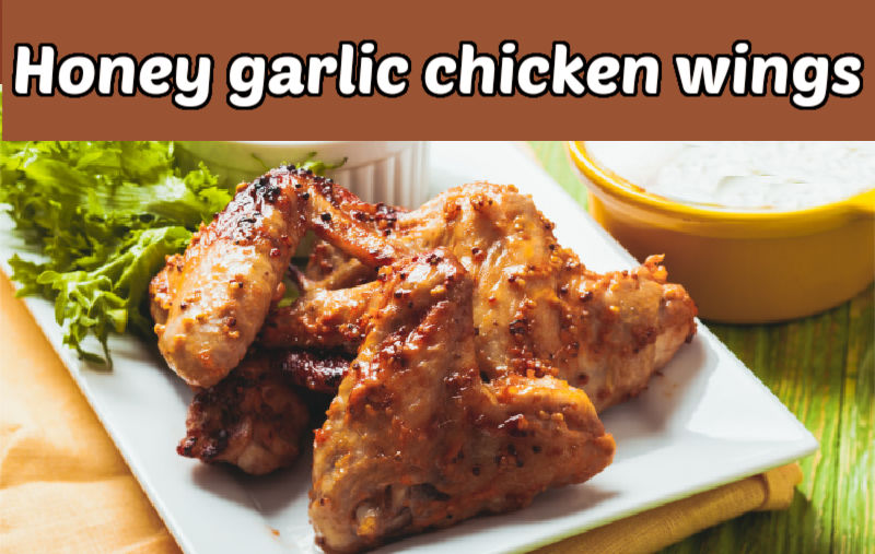 Seasoned chicken wings recipe on a white plate with a salad. Tan text box reads honey garlic chicken wings.