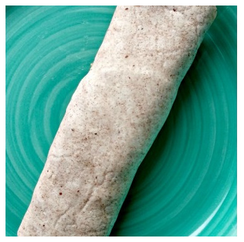  A filled tortilla on a green plate rolled into a cylinder.