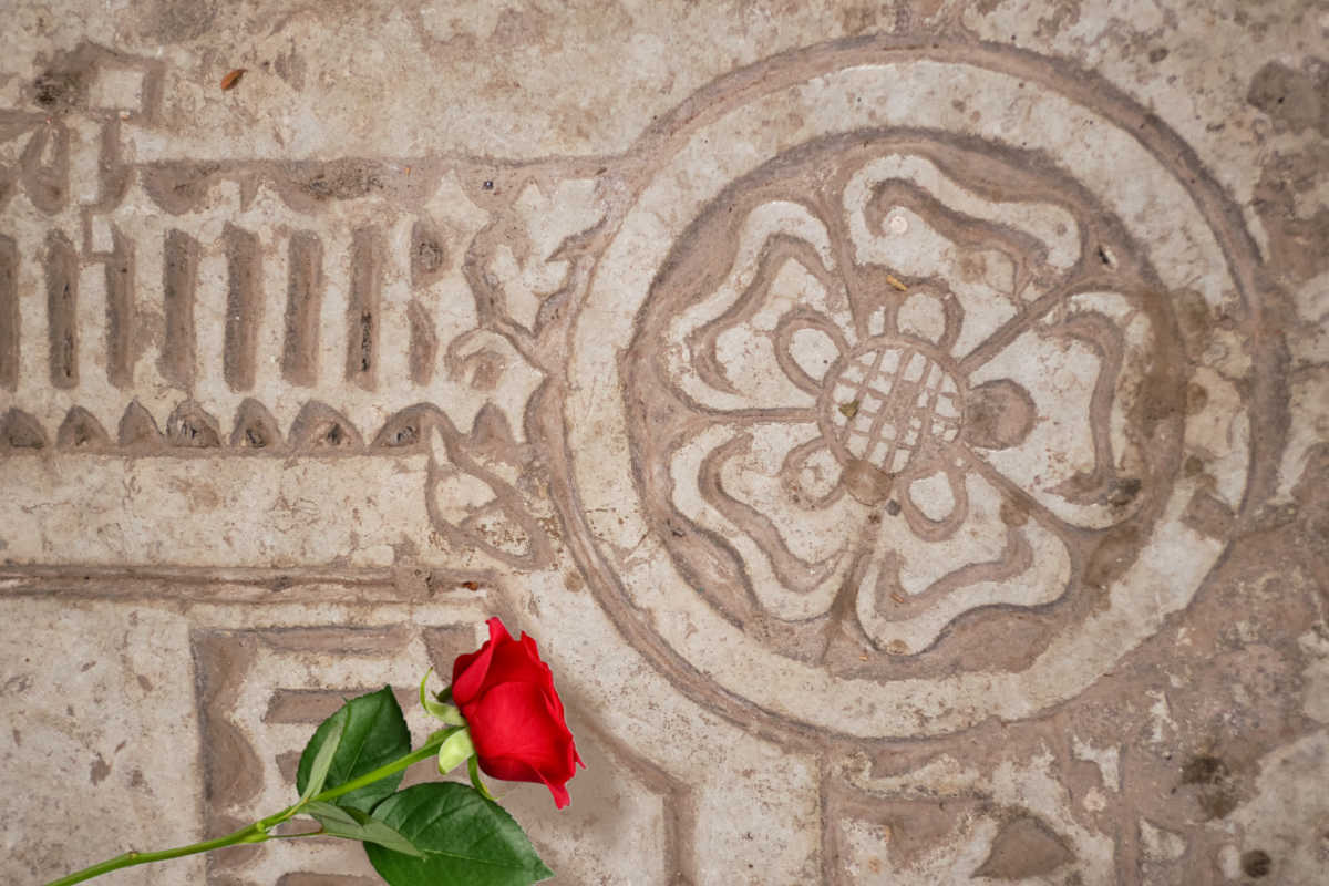 A carved rose symbol with red rose in front indicating rose color symbolism.