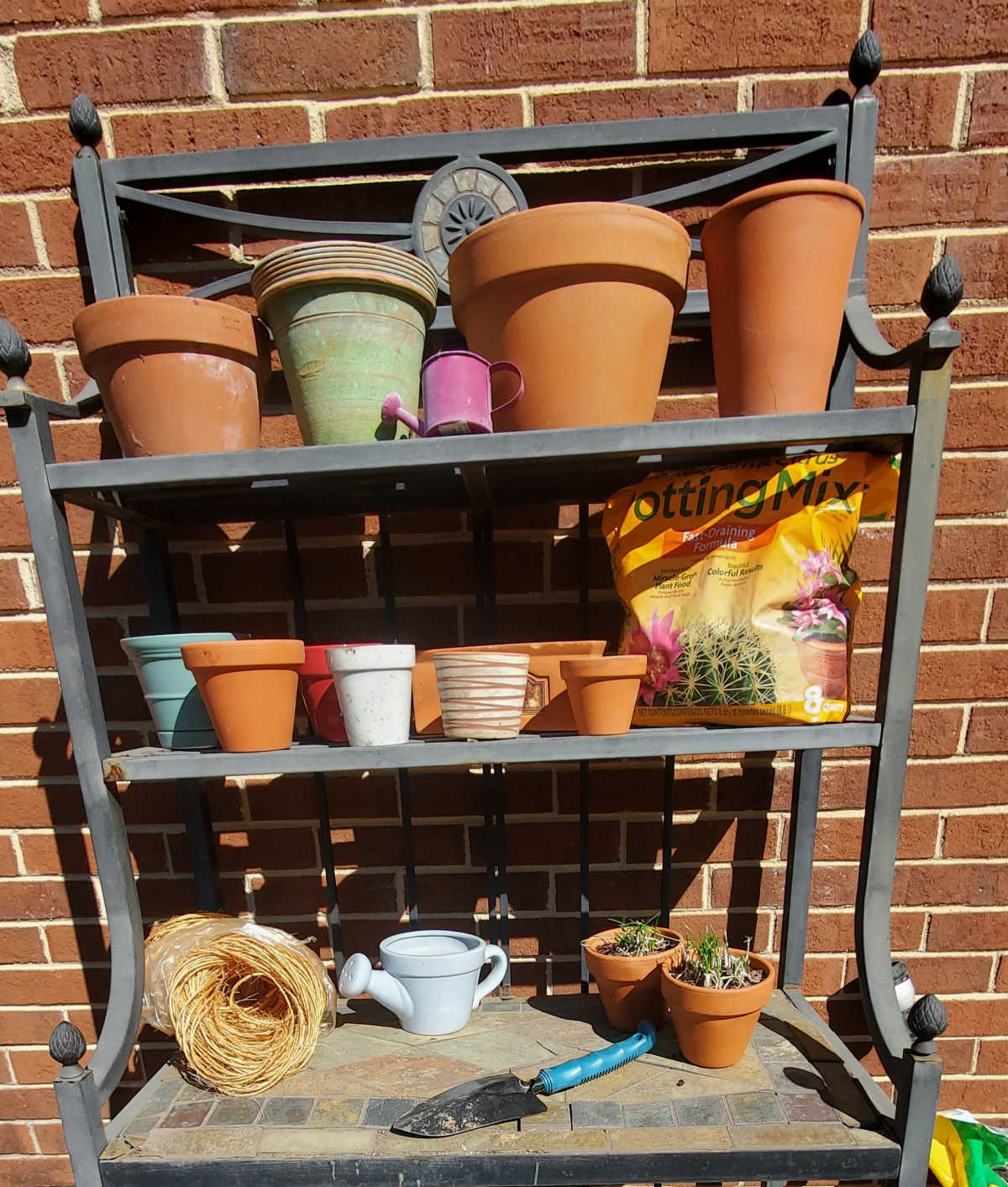 A vegetable deck garden stand holding tools, pots and soil.