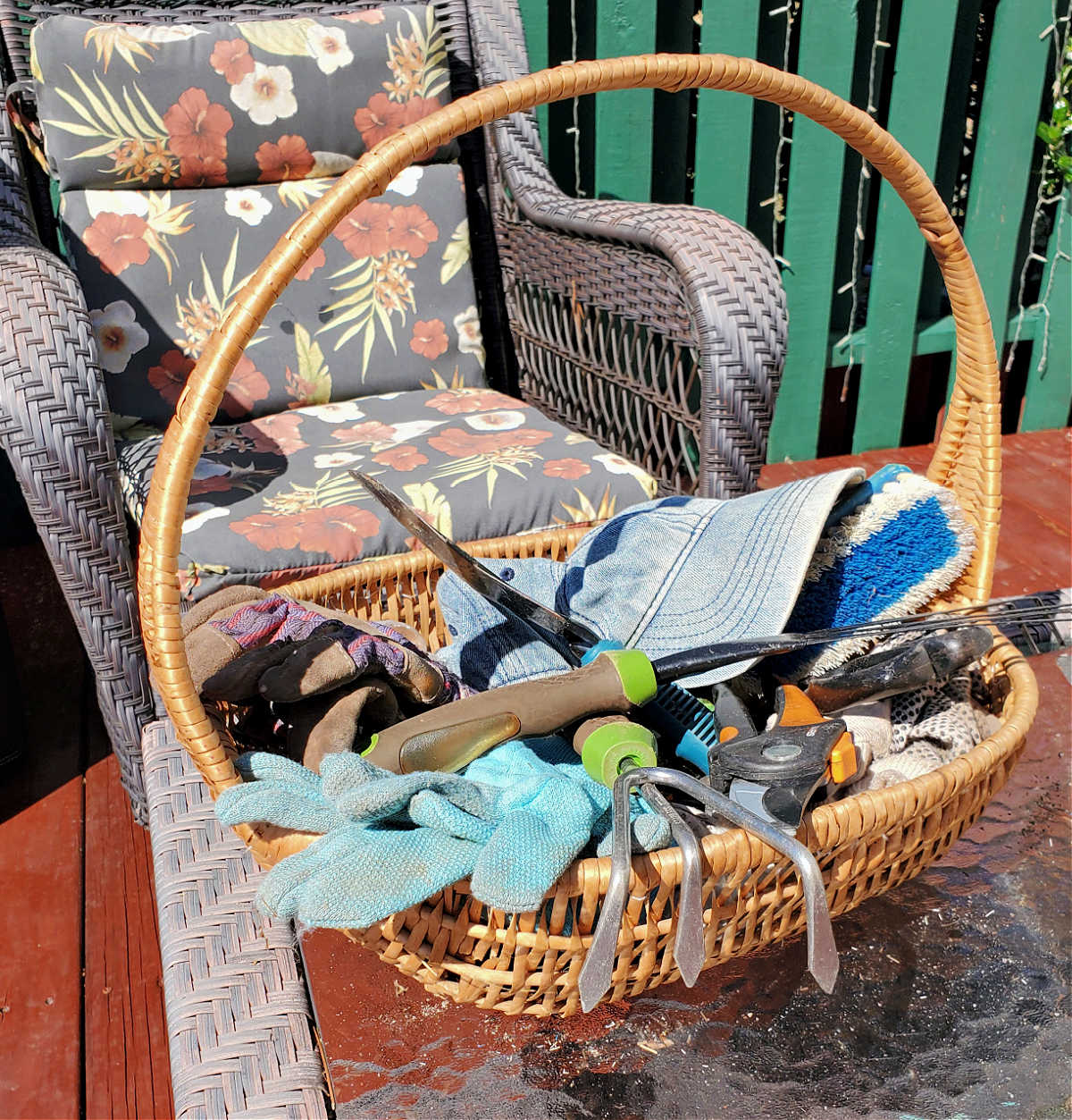 A basket holding toolls for gardening next to a patio chair.