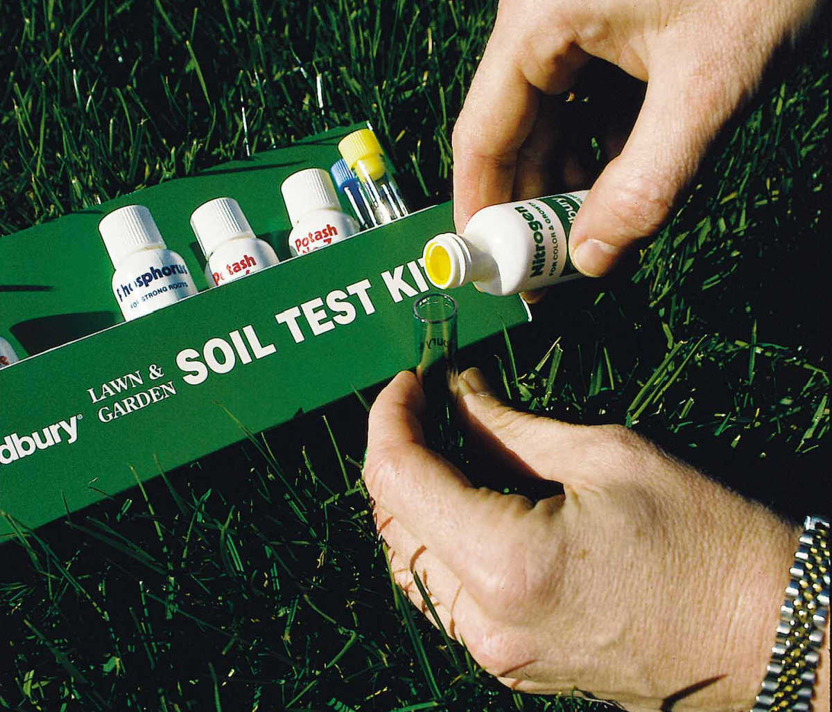 Hands holding a soil testing kit used to test garden soil pH.