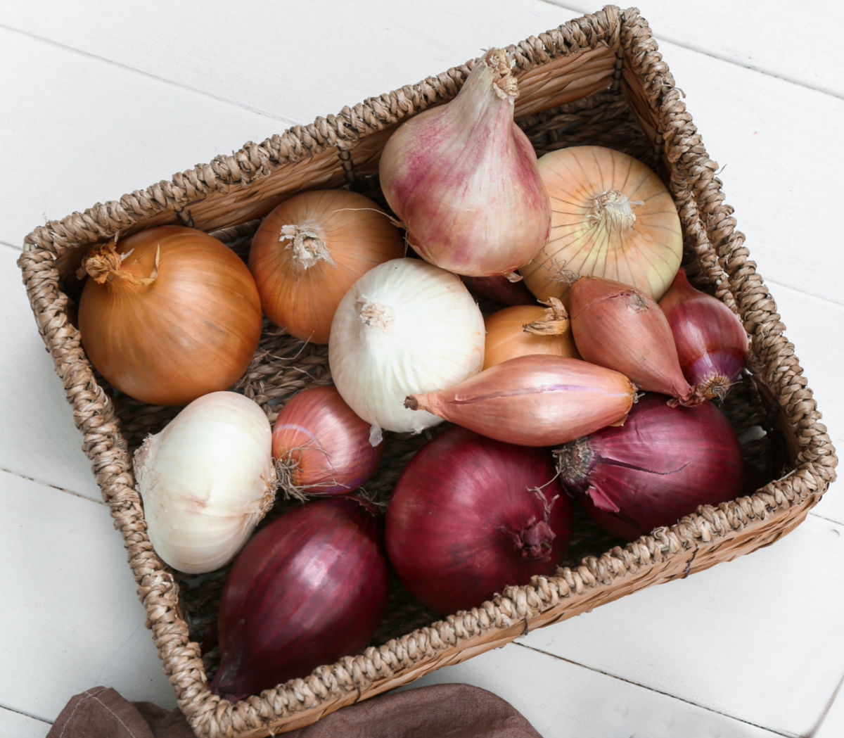 A basket filled with shallots and other alliums.