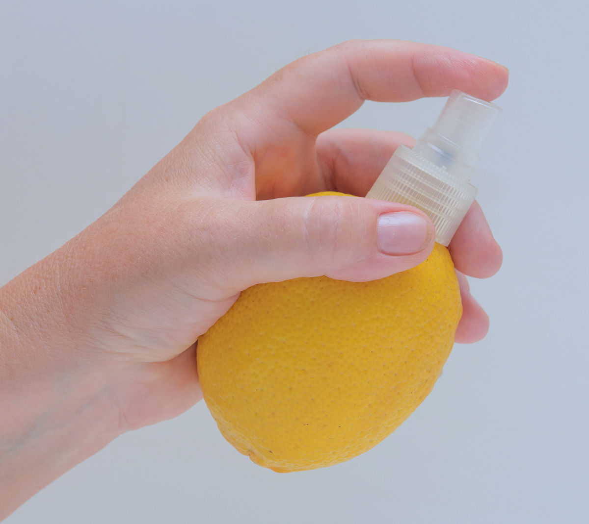 A woman holding a lemon with a spray nozzle attached to it.