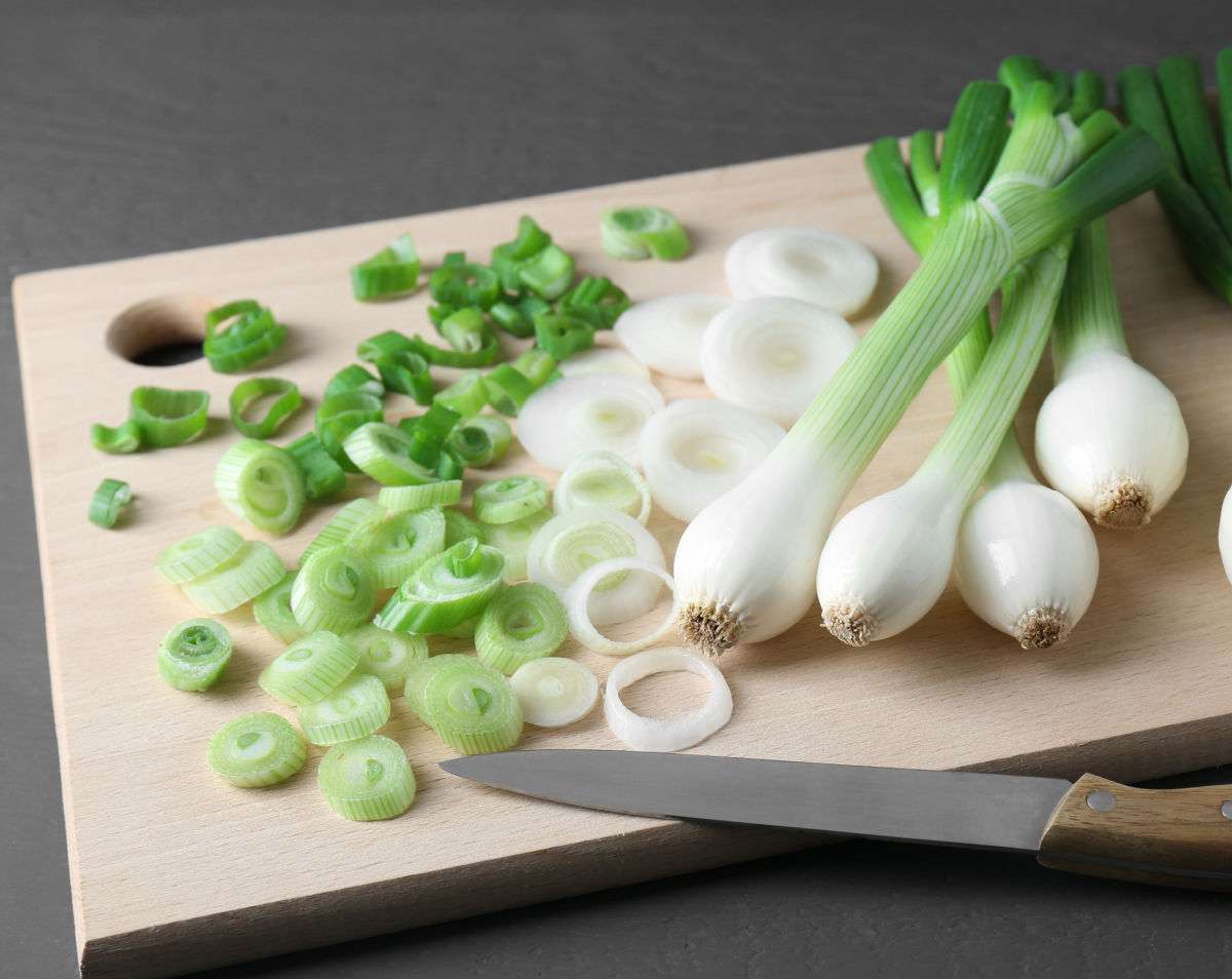 Sliced white and light-green parts of spring onions on a cutting board.