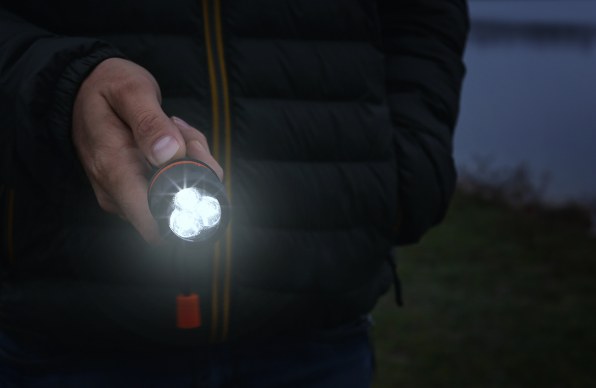 A man holding a flash bugs to look for squash bugs at night.