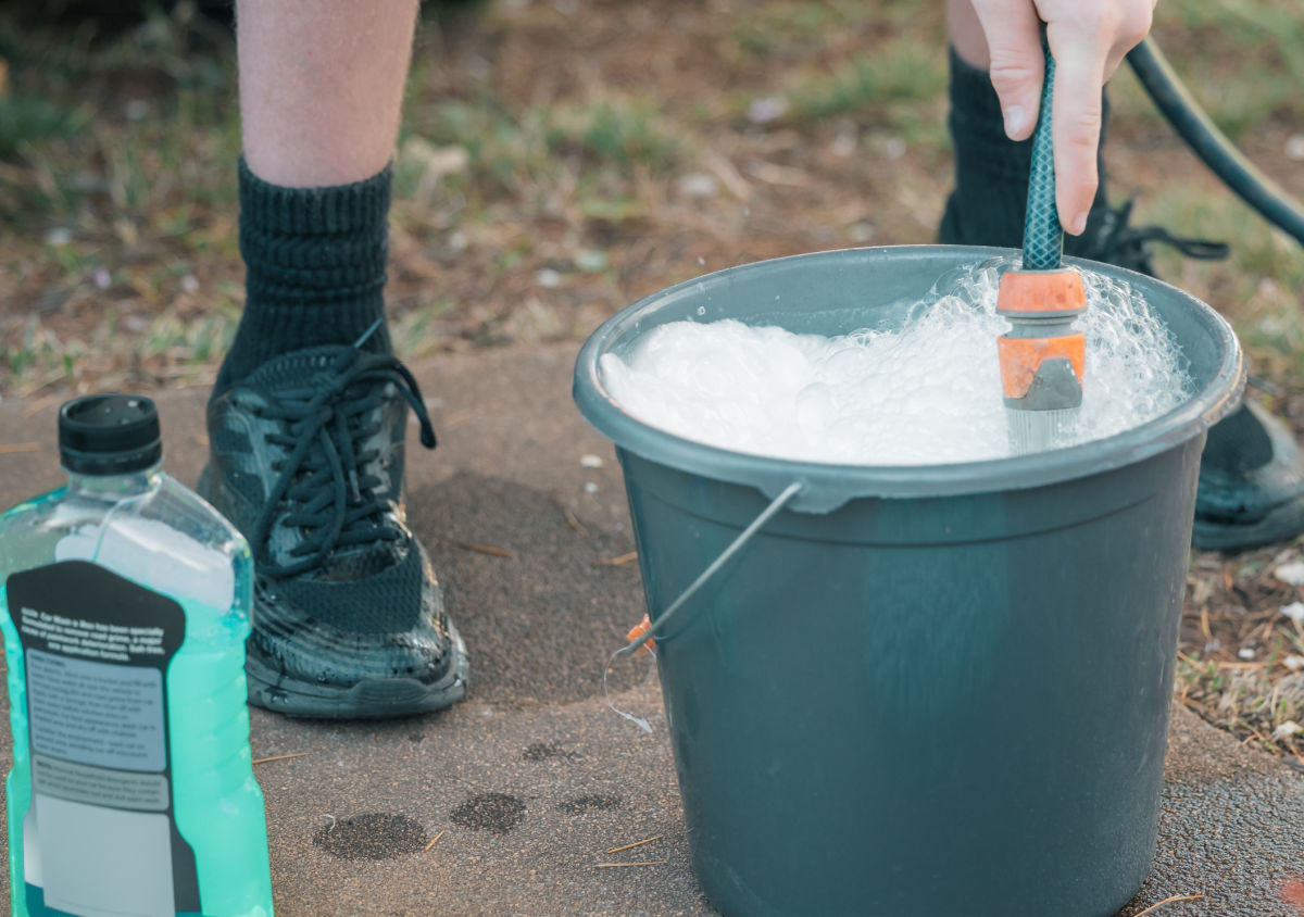 A boy filling a buciket with soapy water to kill squash bugs.