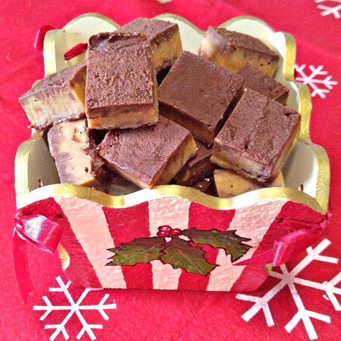 A striped Christmas box that is open and filled with one of my favorite Christmas fudge flavors, peanut butter swirl fudge.